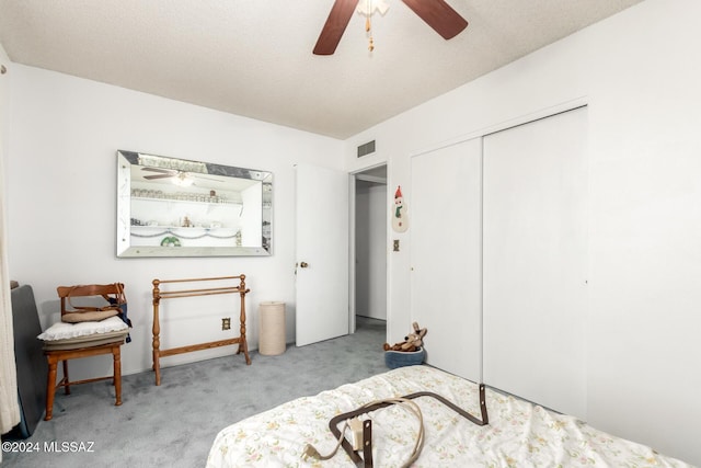 carpeted bedroom with ceiling fan, a textured ceiling, and a closet