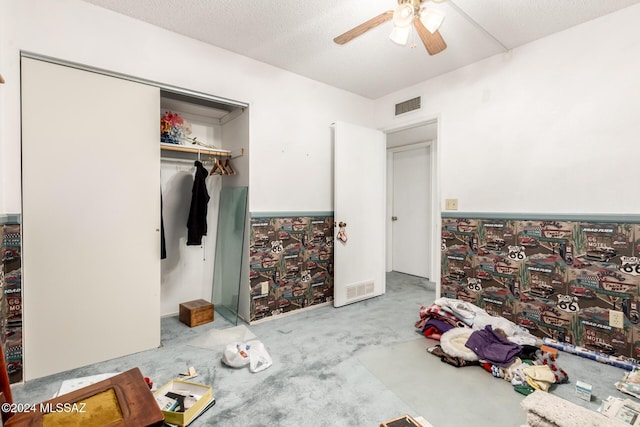 carpeted bedroom with a textured ceiling, a closet, and ceiling fan