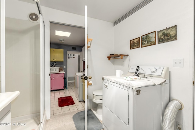 washroom with light tile patterned floors, washer / clothes dryer, and crown molding