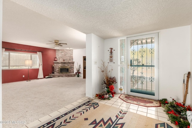 carpeted foyer entrance featuring a textured ceiling, ceiling fan, and a fireplace