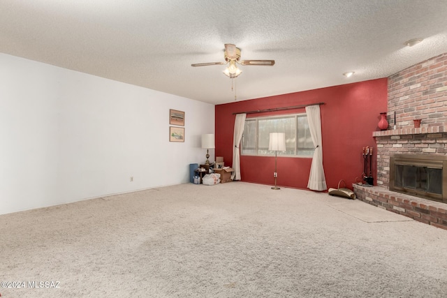 unfurnished living room featuring a fireplace, a textured ceiling, carpet flooring, and ceiling fan