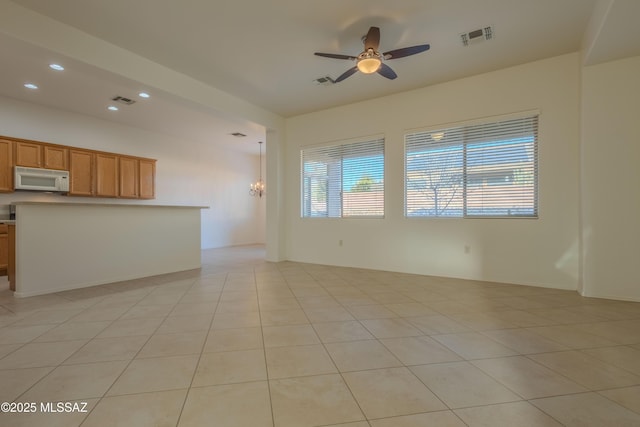 unfurnished living room with ceiling fan with notable chandelier and light tile patterned floors