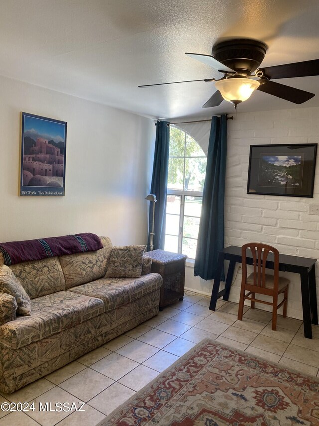 living room with a textured ceiling, ceiling fan, and light tile patterned flooring