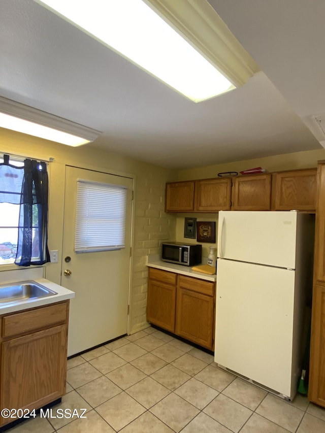 kitchen with white fridge, light tile patterned flooring, and sink