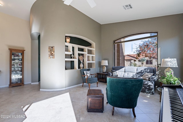 tiled living area featuring high vaulted ceiling, visible vents, baseboards, ceiling fan, and built in shelves