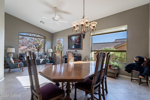 tiled dining space with ceiling fan with notable chandelier and lofted ceiling