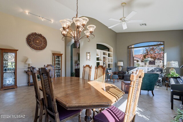 tiled dining space featuring ceiling fan with notable chandelier and vaulted ceiling