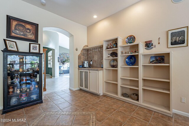 interior space with white cabinetry, light tile patterned flooring, and lofted ceiling