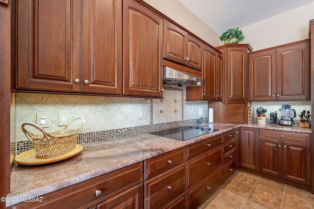 kitchen featuring black electric cooktop, backsplash, under cabinet range hood, and light stone counters