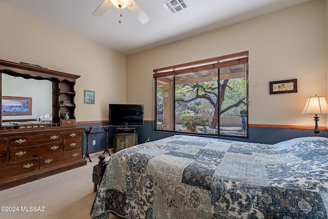 carpeted bedroom with visible vents, ceiling fan, and wainscoting