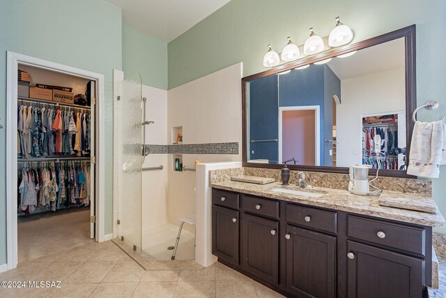 bathroom featuring tile patterned floors, vanity, and tiled bath