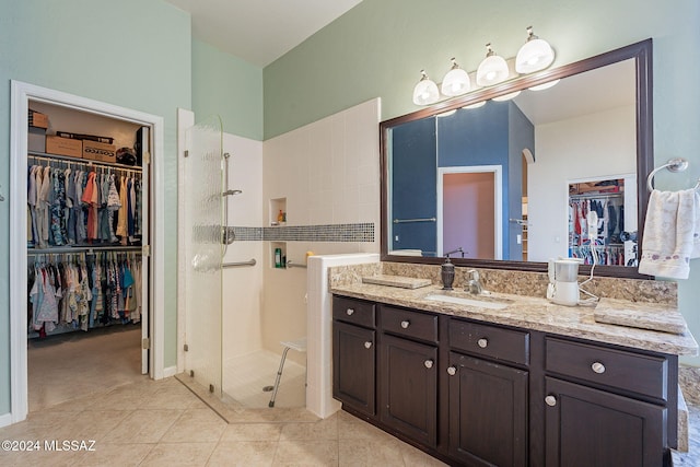 full bath with vanity, tile patterned floors, a spacious closet, and a shower stall