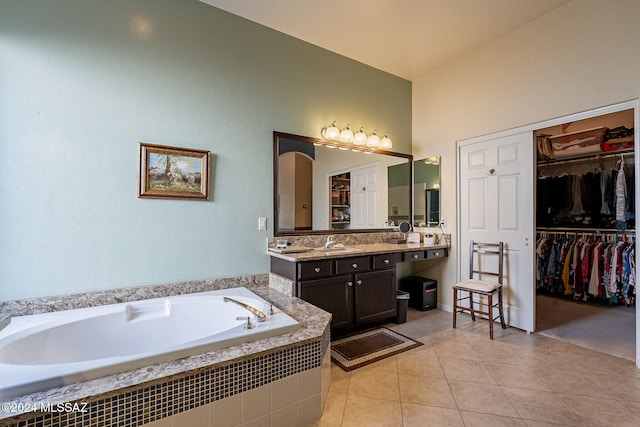 bathroom with tile patterned flooring, vanity, a relaxing tiled tub, and vaulted ceiling