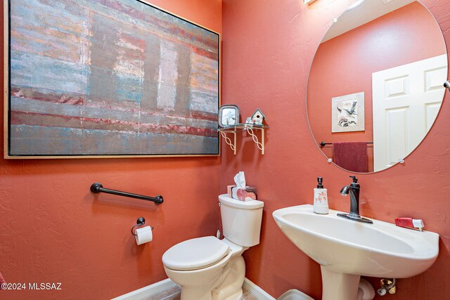 bathroom with toilet, a sink, and baseboards
