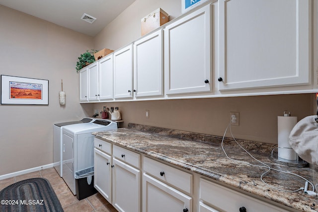 laundry area with washing machine and dryer, light tile patterned floors, baseboards, visible vents, and cabinet space