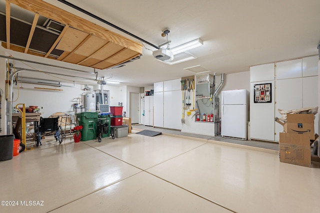 garage with water heater, a garage door opener, and freestanding refrigerator