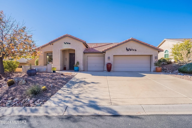 mediterranean / spanish-style house featuring a tile roof, stucco siding, a garage, and driveway