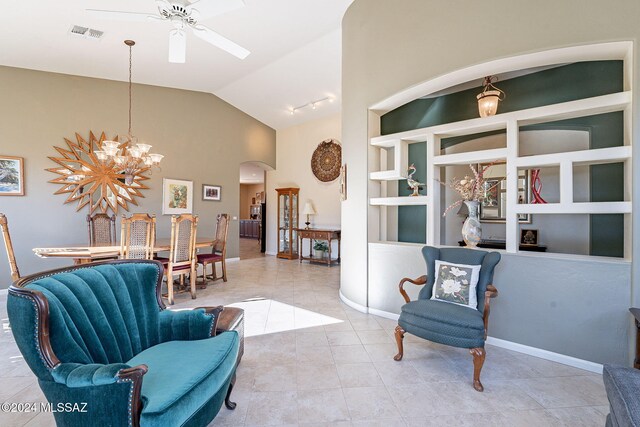 sitting room with built in shelves, ceiling fan with notable chandelier, vaulted ceiling, and light tile patterned flooring