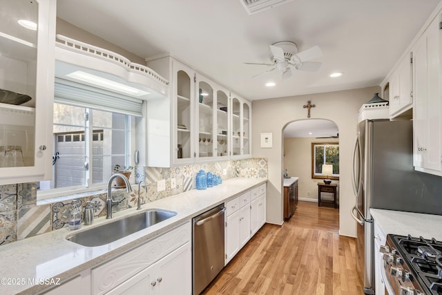 kitchen with a wealth of natural light, white cabinetry, dishwasher, sink, and backsplash