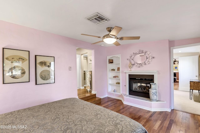 bedroom featuring dark hardwood / wood-style flooring, a fireplace, and ceiling fan