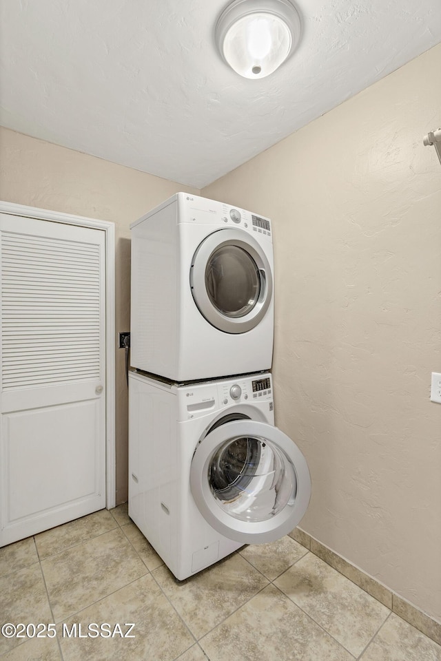 laundry area with stacked washer and dryer and light tile patterned floors