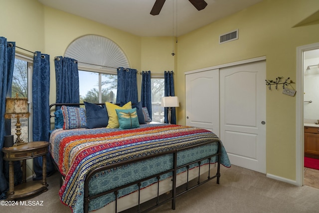 bedroom featuring ceiling fan, a closet, ensuite bathroom, and light colored carpet