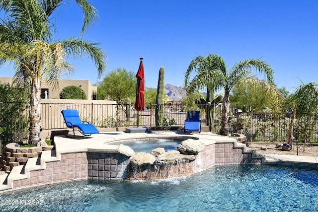 view of swimming pool with pool water feature, a mountain view, and an in ground hot tub