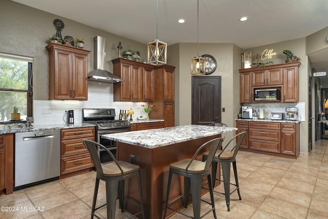 kitchen featuring wall chimney exhaust hood, a center island, stainless steel appliances, and tasteful backsplash