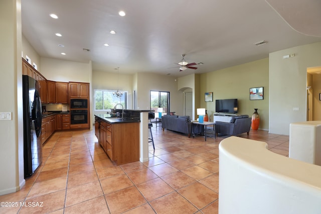 kitchen with recessed lighting, dark countertops, a breakfast bar, and black appliances