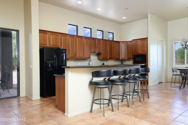 kitchen featuring an island with sink, visible vents, plenty of natural light, and black appliances