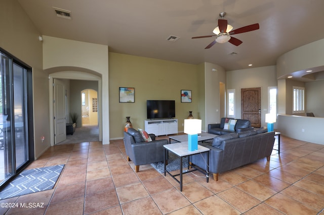 living room with visible vents, arched walkways, ceiling fan, and light tile patterned flooring