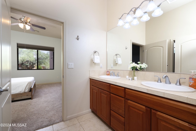 ensuite bathroom with a sink, tile patterned floors, ceiling fan, and double vanity