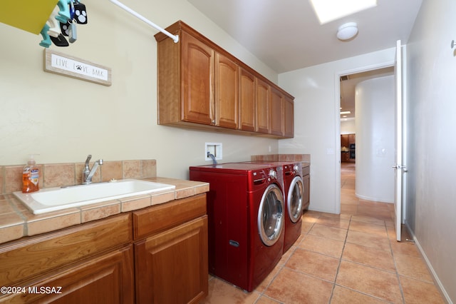 laundry area featuring a sink, cabinet space, light tile patterned floors, and washer and clothes dryer