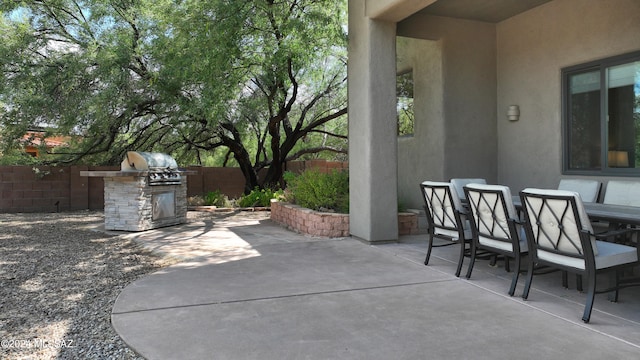 view of patio featuring fence, outdoor dining area, and an outdoor kitchen