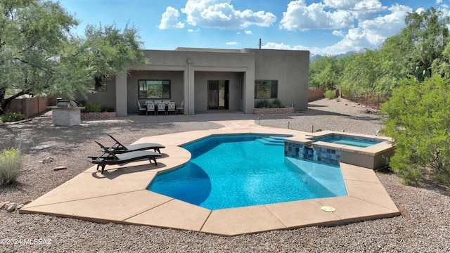 view of swimming pool with a patio area, a pool with connected hot tub, and fence