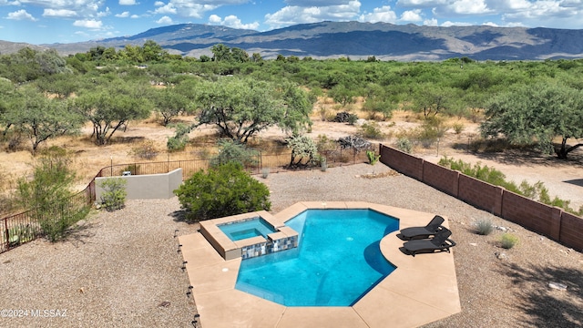 view of swimming pool with a fenced backyard, a mountain view, a pool with connected hot tub, and a patio