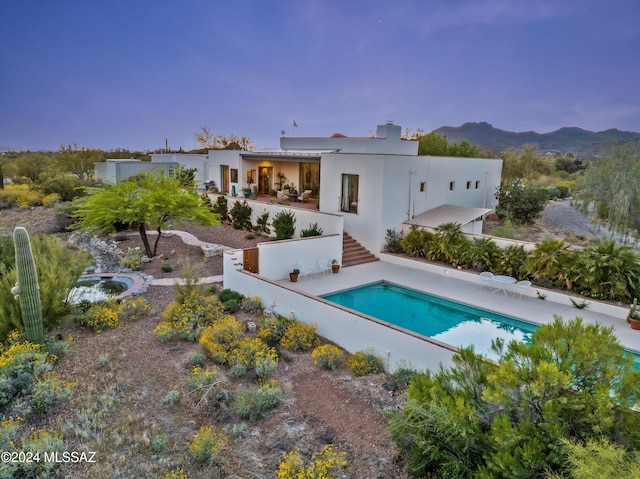 back house at dusk featuring a fenced in pool and a mountain view