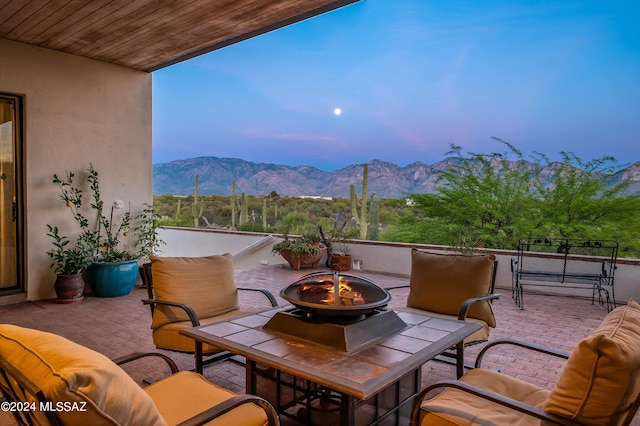 patio terrace at dusk with a mountain view and an outdoor living space with a fire pit