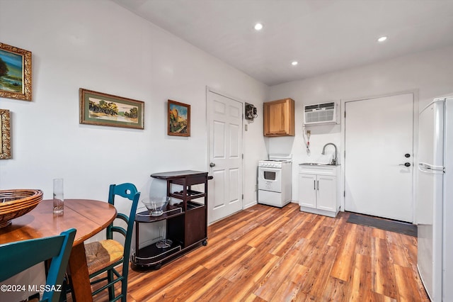 kitchen featuring white appliances, a wall mounted AC, sink, light brown cabinets, and light hardwood / wood-style floors