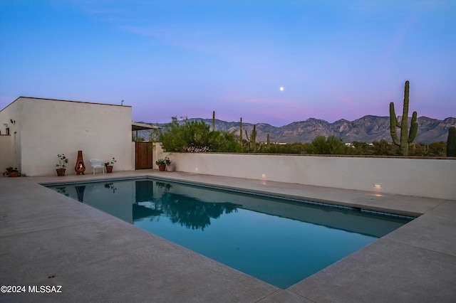 pool at dusk featuring a mountain view