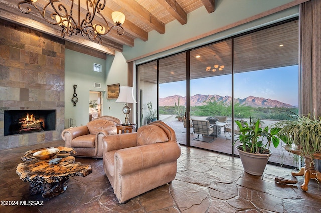 living room with a mountain view, wooden ceiling, a fireplace, beamed ceiling, and plenty of natural light