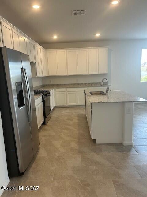 kitchen with black gas range oven, white cabinets, visible vents, a sink, and stainless steel fridge with ice dispenser