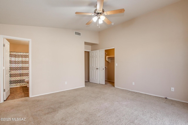 unfurnished bedroom with ensuite bathroom, a closet, light colored carpet, ceiling fan, and lofted ceiling