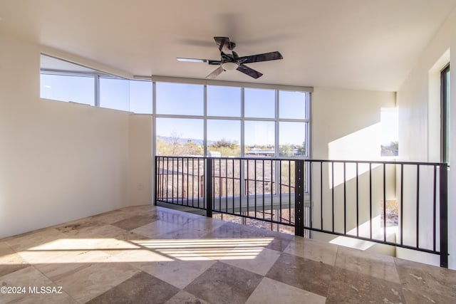 empty room with ceiling fan, expansive windows, and plenty of natural light