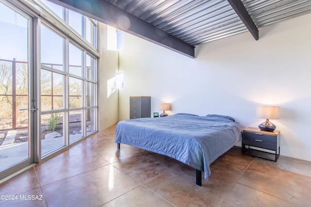 bedroom featuring access to outside, concrete floors, beamed ceiling, and multiple windows