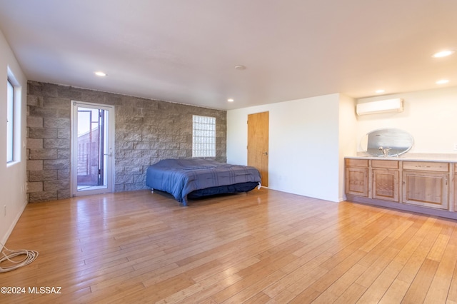 unfurnished bedroom featuring a wall mounted AC, light hardwood / wood-style flooring, and access to exterior