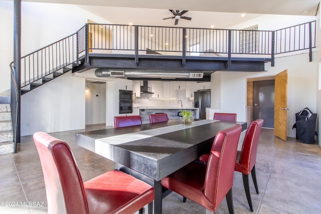 dining space featuring a high ceiling, ceiling fan, concrete floors, and sink