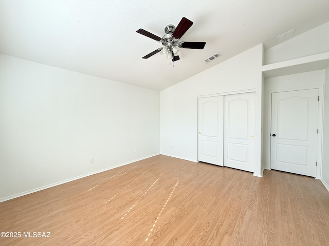 unfurnished bedroom with a closet, ceiling fan, vaulted ceiling, and light wood-type flooring