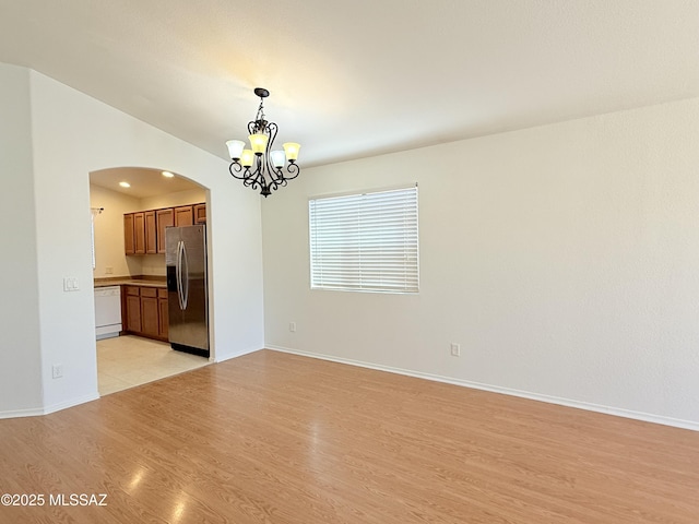 empty room featuring a chandelier and light hardwood / wood-style floors