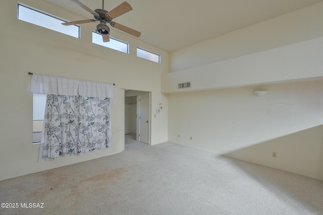 unfurnished room with light carpet, a towering ceiling, and ceiling fan